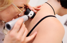 [Translate to Japanese:] Physician looking on skin of patient with an miscroscope instrument