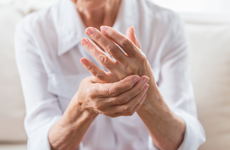 [Translate to Japanese:] Person in white blouse holding left hand with right hand